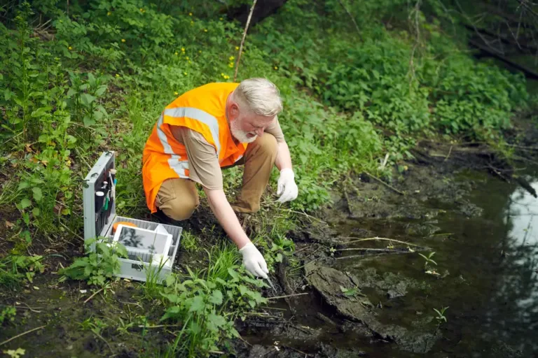 A surveyor testing water quality on a riverbank