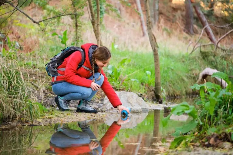 An ecologist taking a freshwater sample in woodland